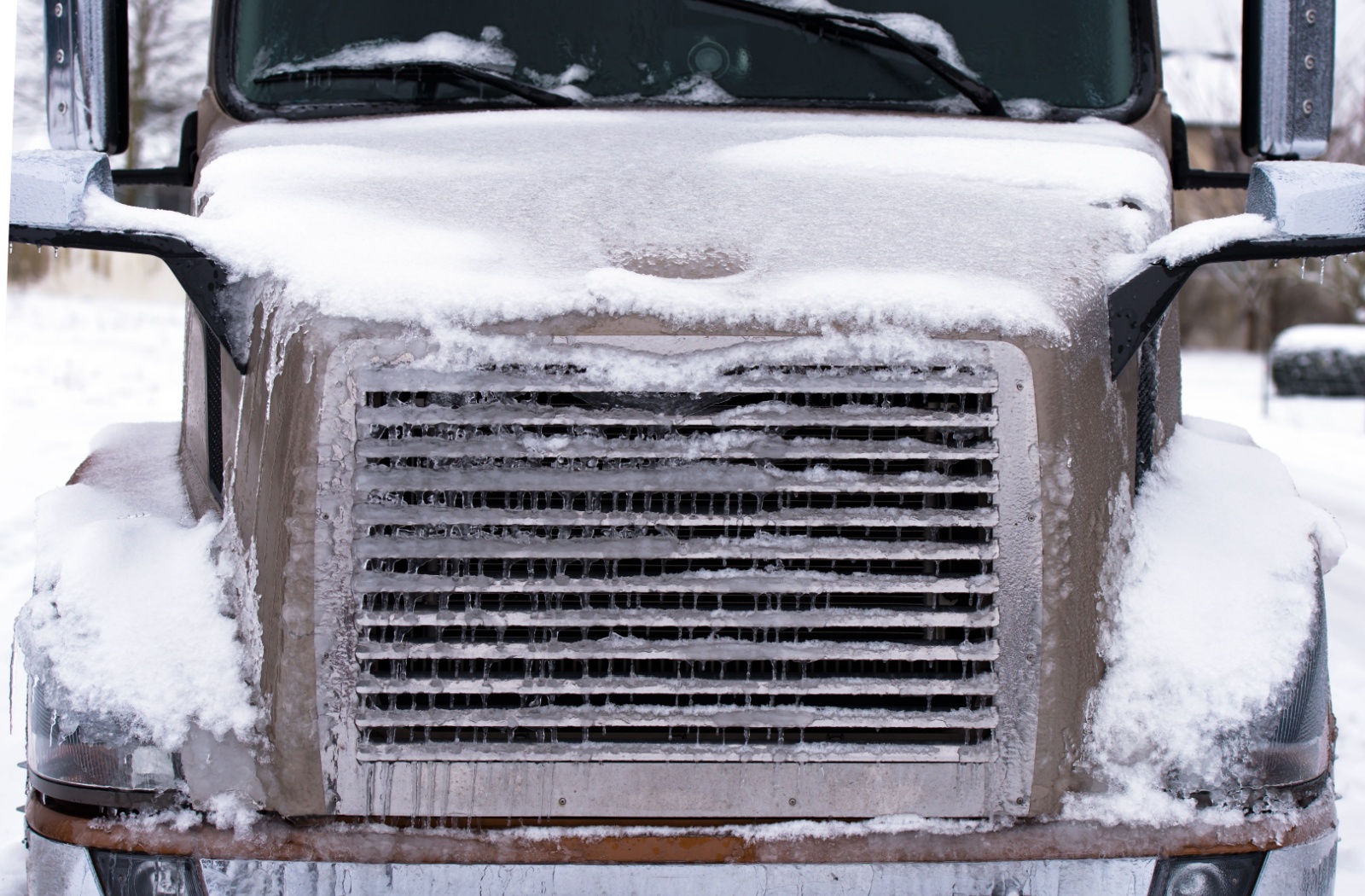 The front grille of a truck completely covered in ice after being used in the wintertime without a front grille cover