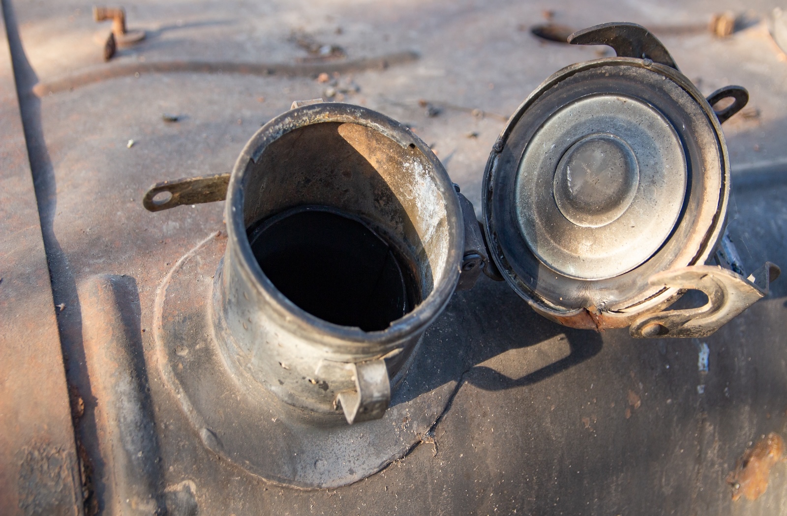 A close-up of a rusted gas tank's open mouth.