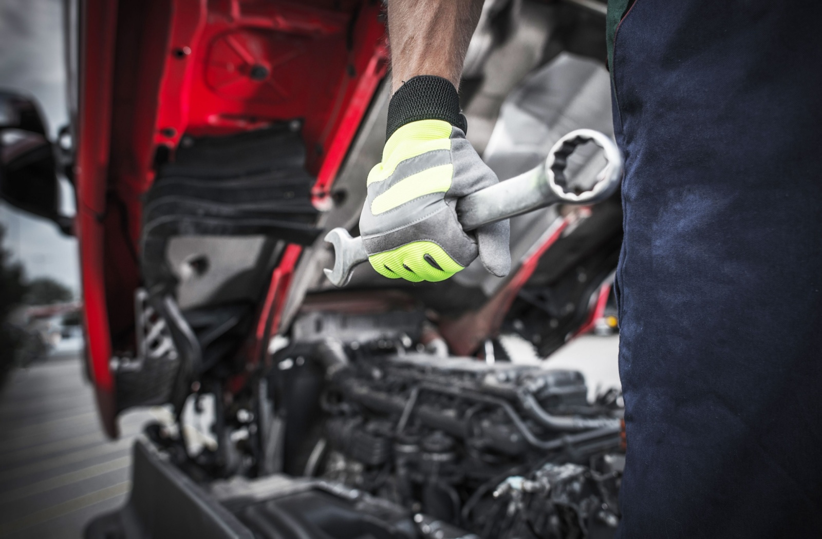 A close-up image of a mechanic holding a wrench after working on an opened Kubota engine on a Kubota tractor.