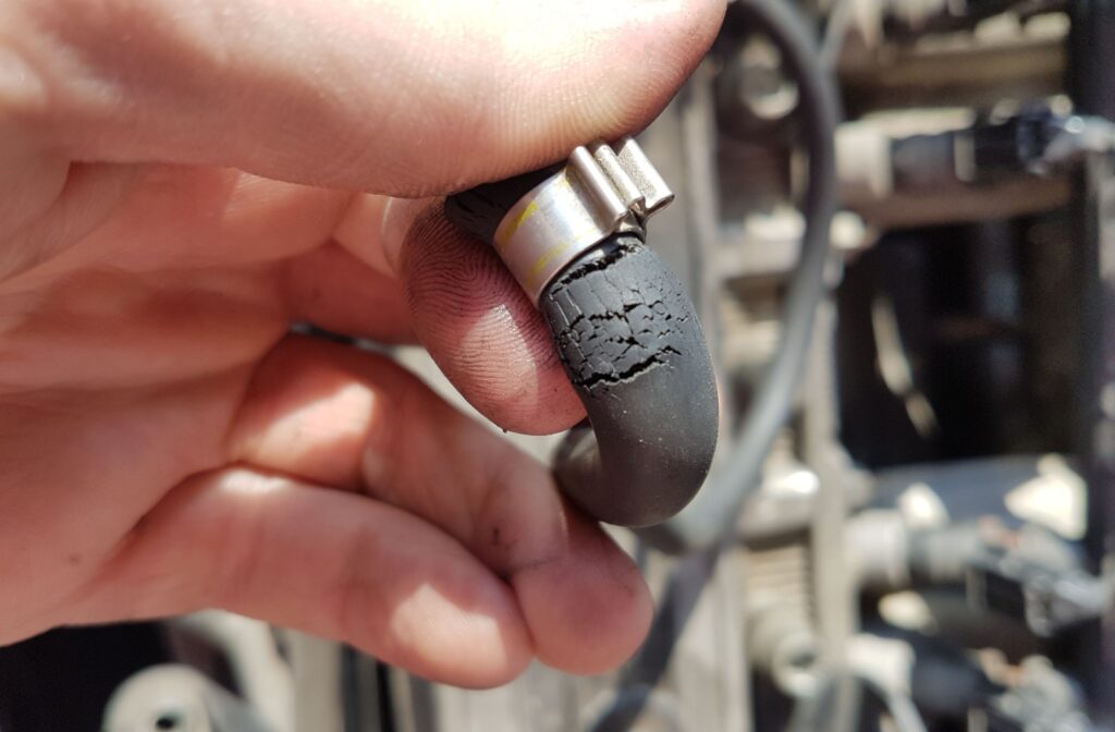 Close-up of someone's hand showing a cracked radiator hose.