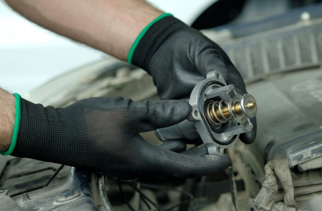 A technician replaces an automotive thermostat to fix cooling issues.