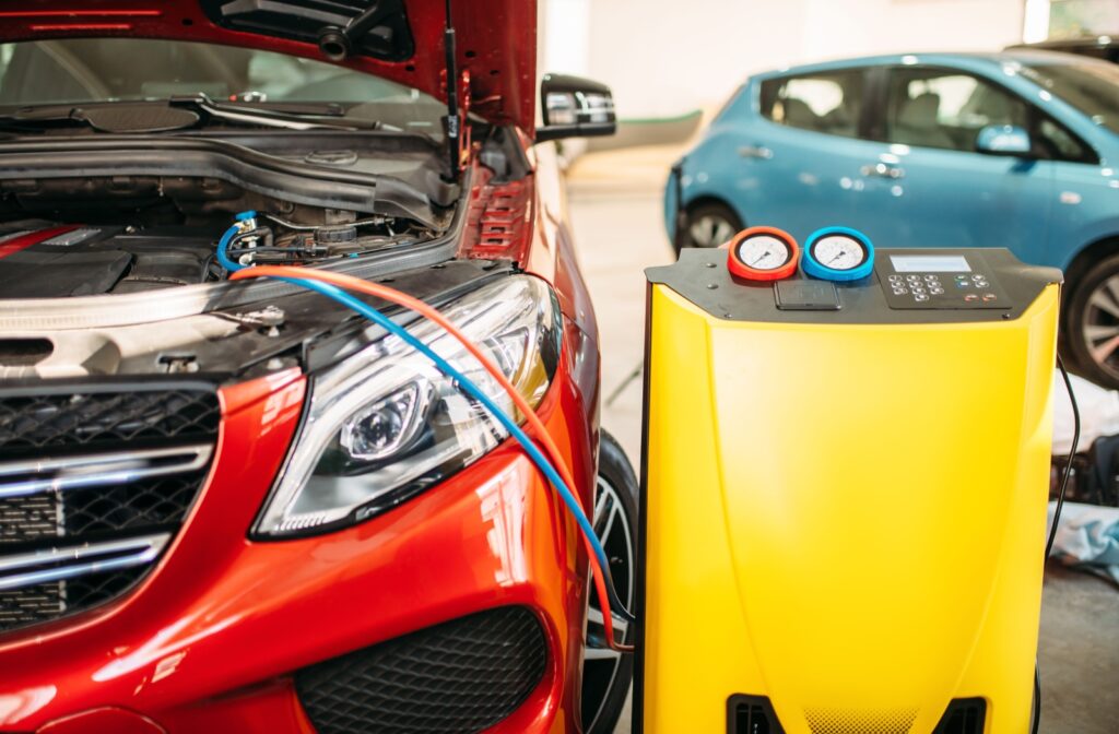 Vehicle connected to an A/C service machine with gauges during a refrigerant recharge process.