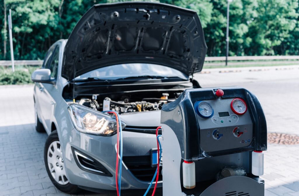 A silver car with its hood open connected to automotive A/C diagnostic and recharge equipment, representing air conditioning repair and maintenance at City Wide Radiator in Calgary.