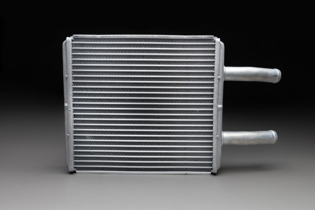 Automotive heater core component isolated on black background, showing the radiator-style part responsible for heating vehicle interior.