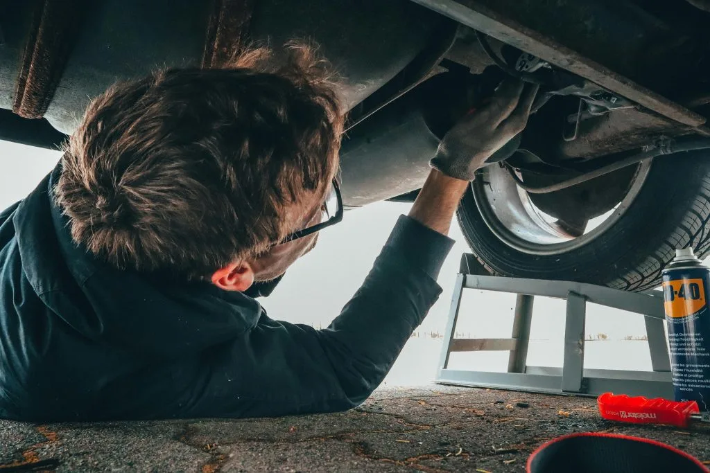 A person is repairing a vehicle while lying underneath it