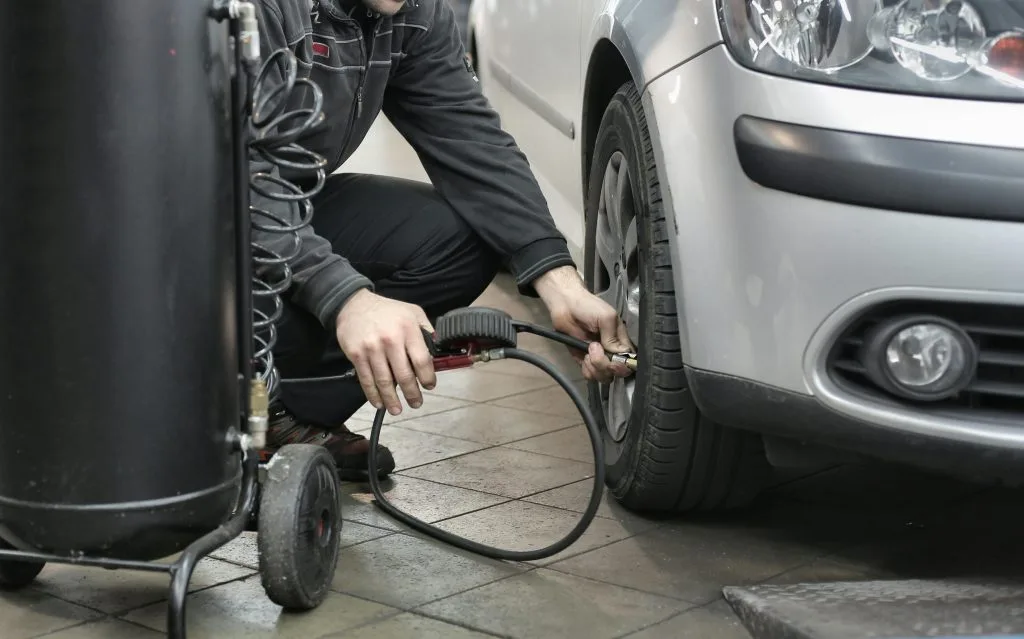 A person is inflating a car tire using an air compressor