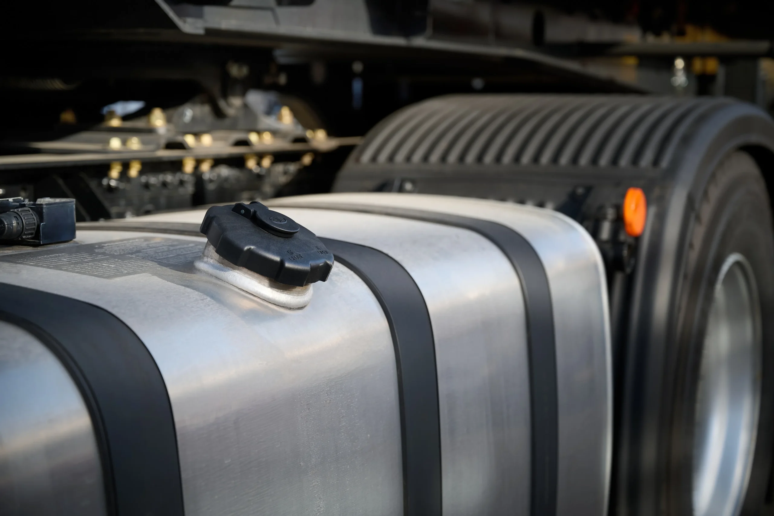 Shiny metal fuel gas tanks placed beside a large truck wheel