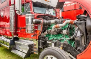 A red truck's engine is exposed, showcasing intricate machinery and vibrant components