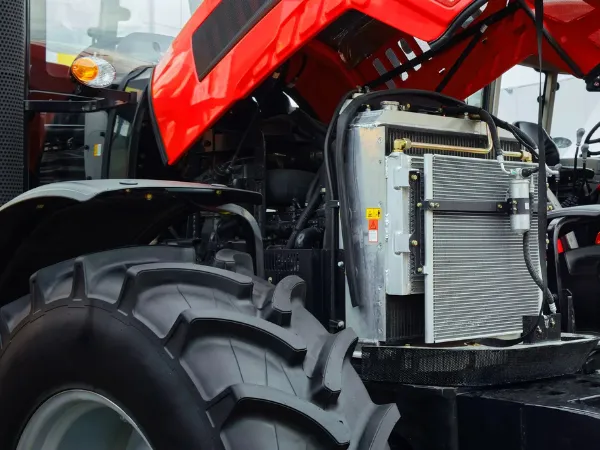 Bright red tractor features exposed engine compartment and large tire, highlighting industrial radiators