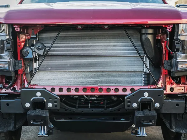 Radiator repair process shown with exposed components of a red truck's front