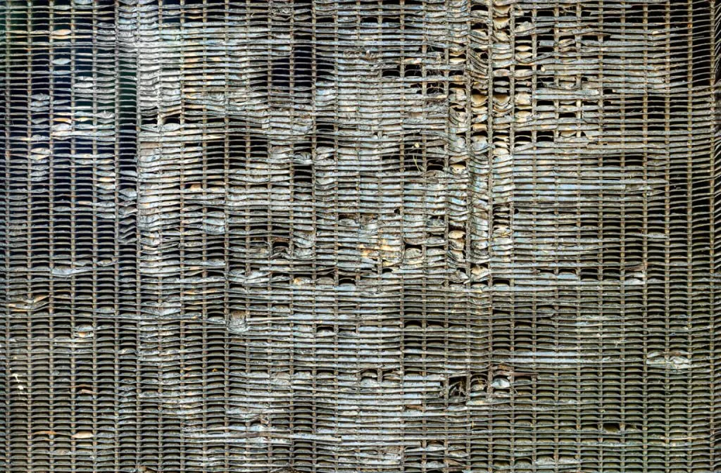 A textured surface displays a mix of metallic lines and worn, damaged areas