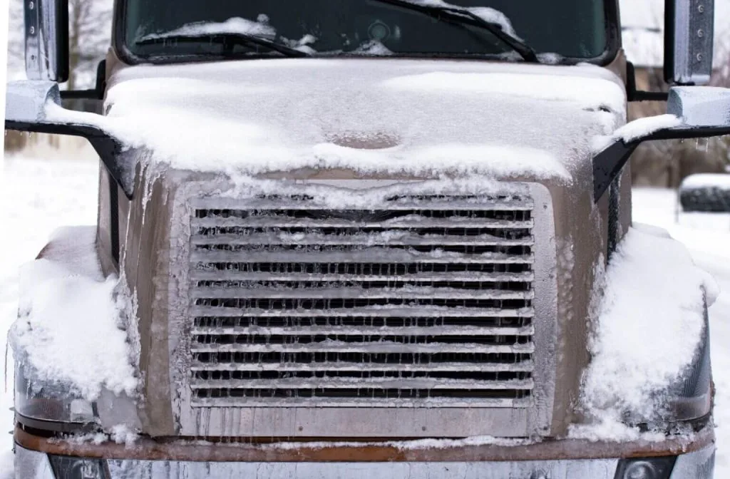 A large truck is covered in a thick layer of snow and ice