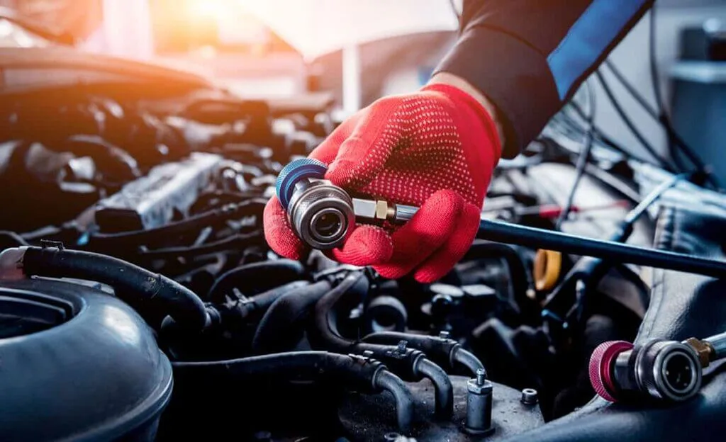 A person wearing gloves is tightening a fitting on an engine