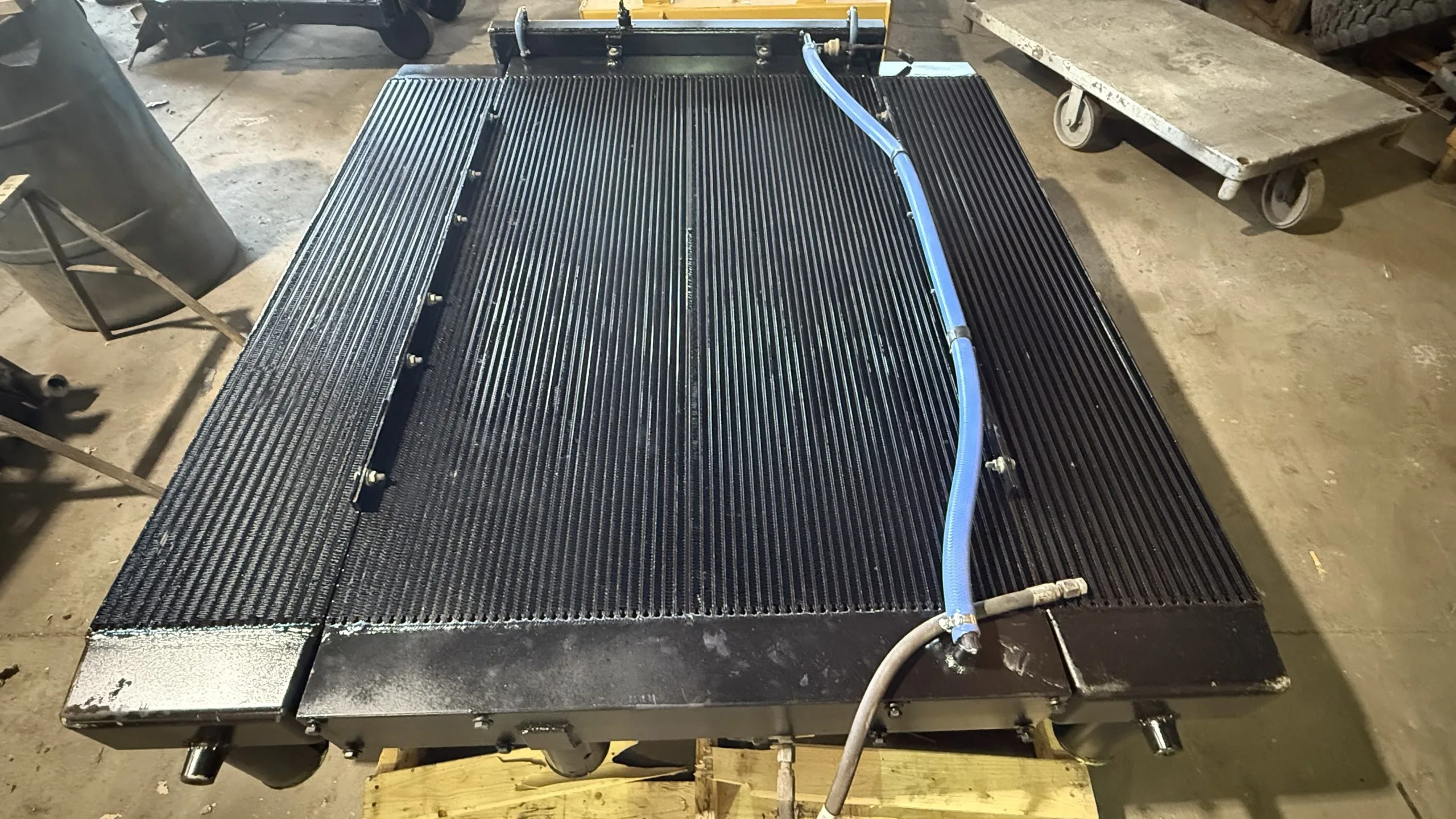 A large, black industrial component with a blue hose attached rests on a surface