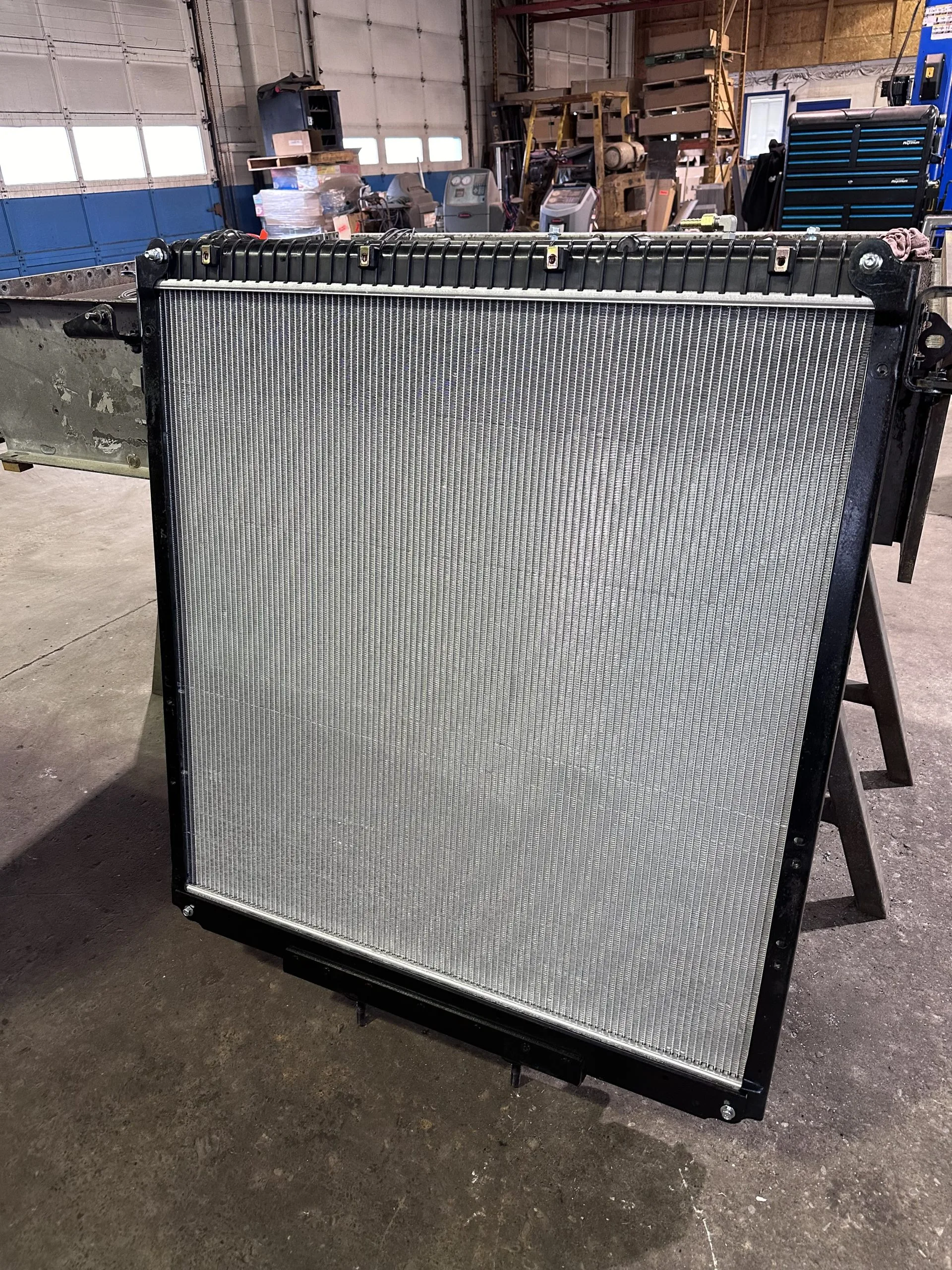 A large, flat, metal grid stands upright on a rack in a workshop