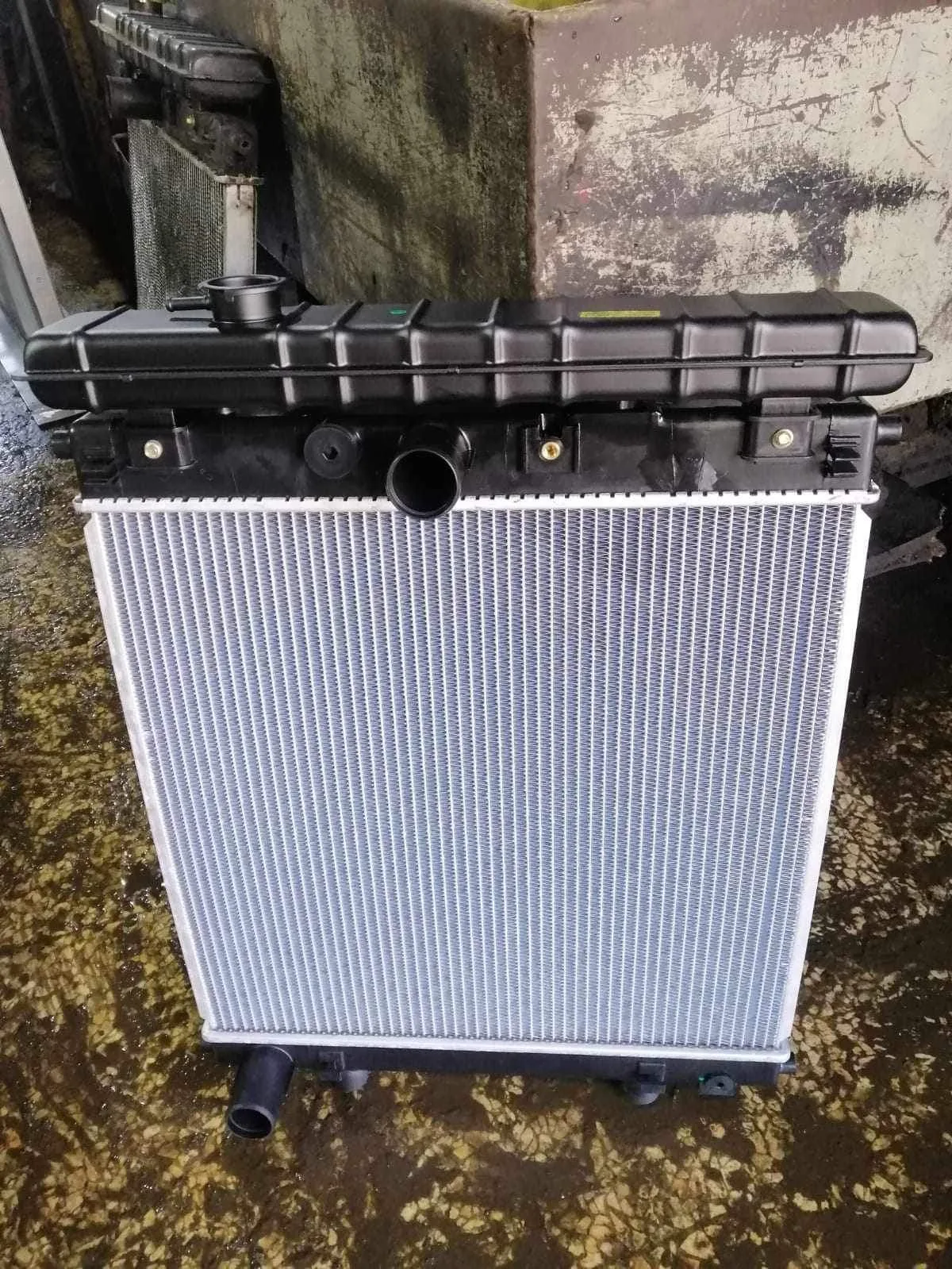 A new car radiator is displayed against a textured background